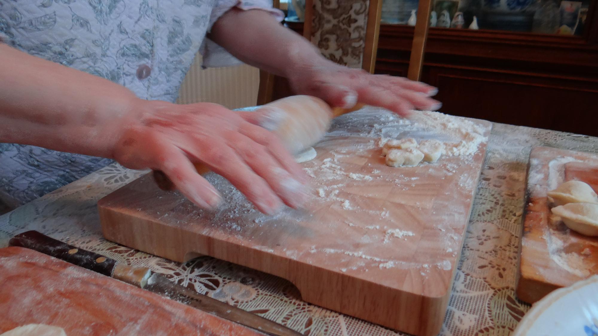 Close hands preparing dough on wooden board